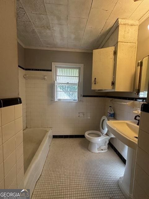 151 Lorrie St, Sardis, GA 30456 - bathroom featuring tile walls, a tub to relax in, a wainscoted wall, and tile patterned flooring