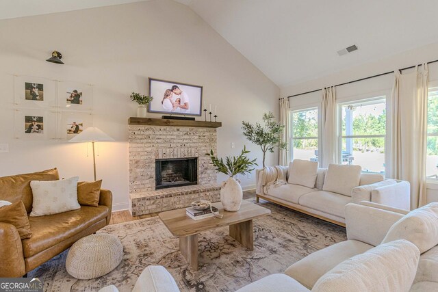 living room with hardwood / wood-style flooring, a brick fireplace, and high vaulted ceiling