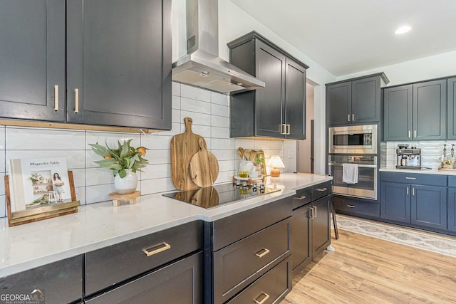 kitchen featuring decorative backsplash, stainless steel appliances, light hardwood / wood-style flooring, and wall chimney exhaust hood