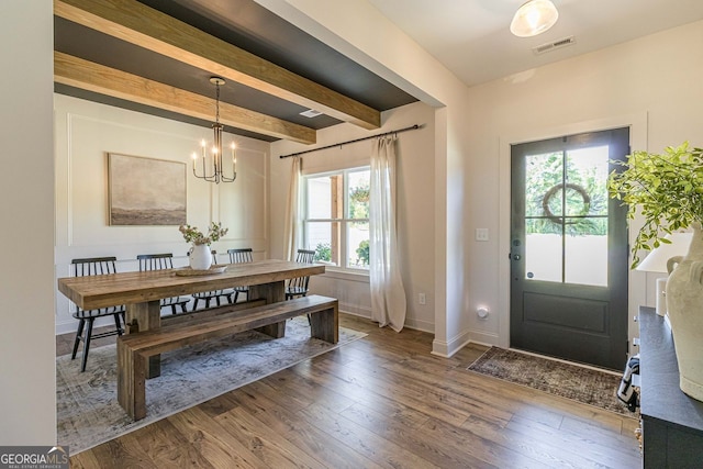 dining area with an inviting chandelier, wood-type flooring, and beam ceiling