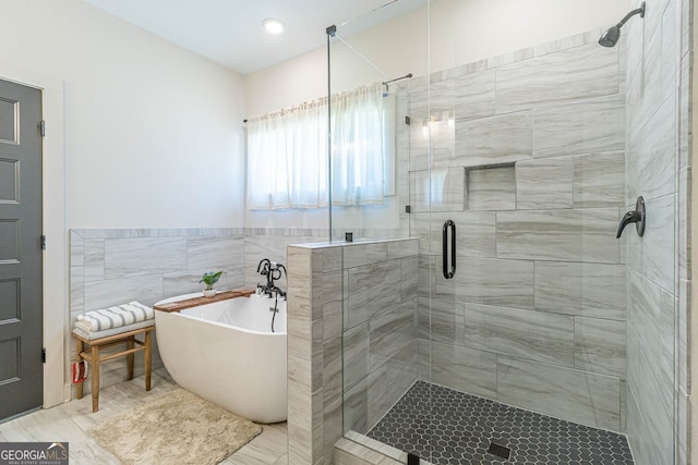 bathroom with plus walk in shower, tile patterned flooring, and tile walls