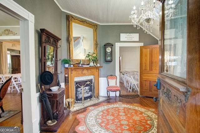 living area featuring wood-type flooring, a premium fireplace, crown molding, and a notable chandelier