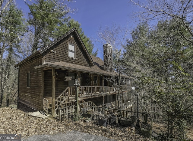 view of front of house with stairs, a chimney, and a wooden deck