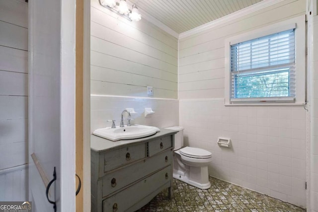 bathroom featuring vanity, toilet, tile walls, and crown molding