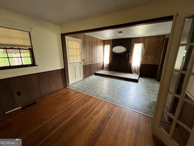 interior space with brick wall, wood-type flooring, and wooden walls