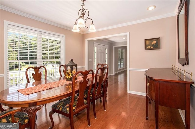 dining room with hardwood / wood-style floors, ornamental molding, and an inviting chandelier