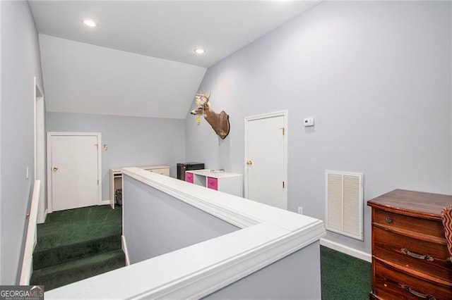 hall with dark colored carpet and vaulted ceiling