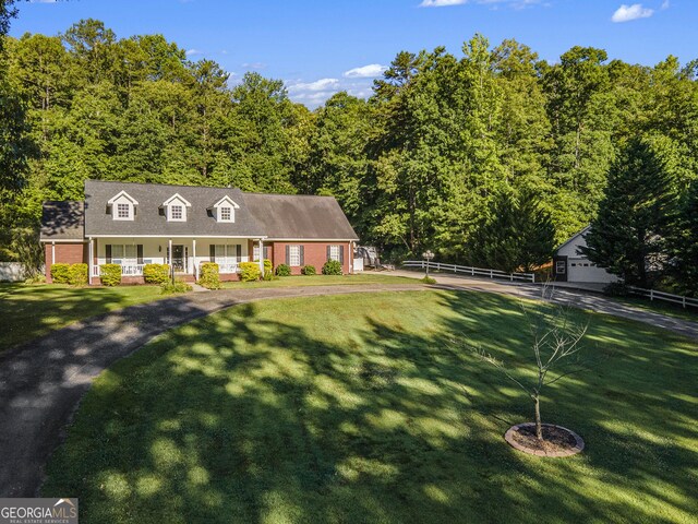 cape cod house featuring a porch and a front lawn