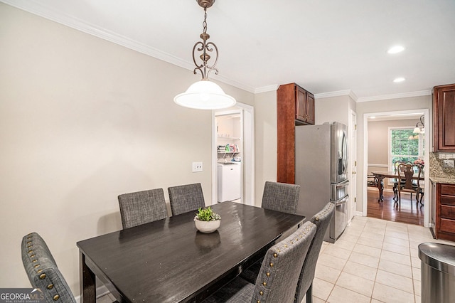 tiled dining room featuring washer / dryer and crown molding