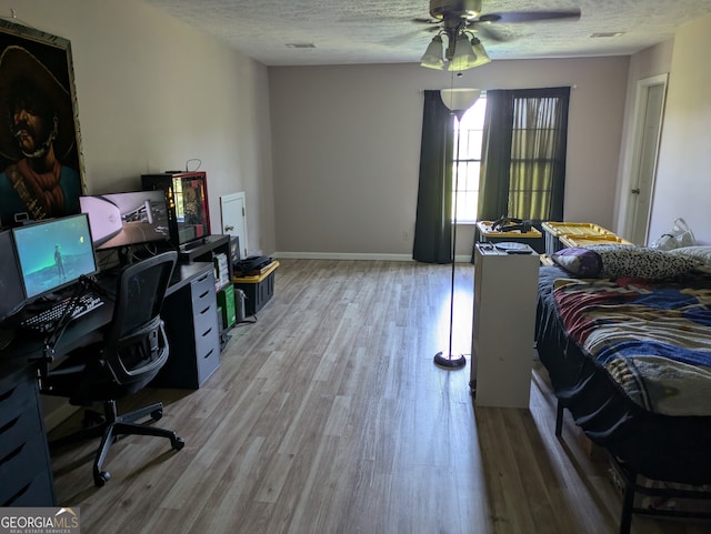 bedroom with a textured ceiling, ceiling fan, and hardwood / wood-style floors