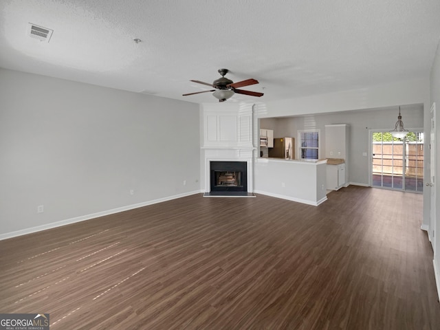 unfurnished living room with visible vents, baseboards, dark wood-type flooring, and a ceiling fan