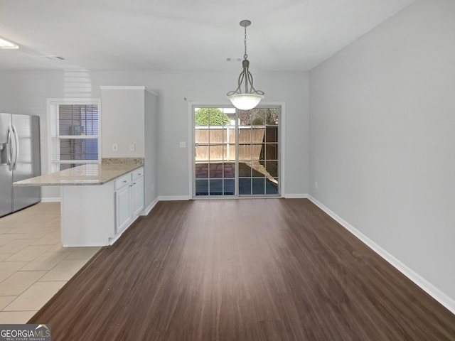 unfurnished dining area featuring visible vents, baseboards, and wood finished floors