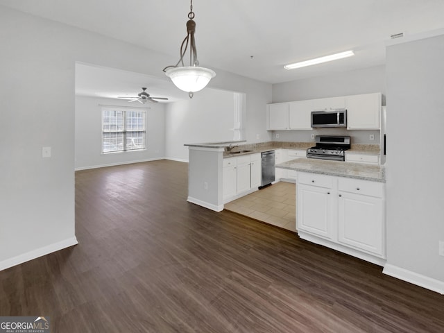 kitchen featuring white cabinetry, a peninsula, dark wood-type flooring, and stainless steel appliances