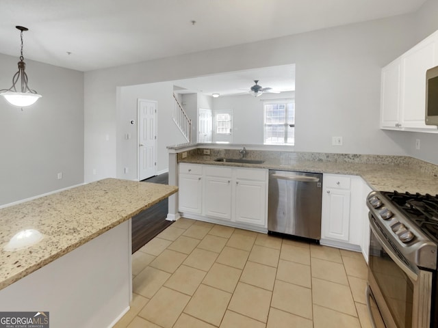 kitchen featuring light stone countertops, a peninsula, a sink, stainless steel appliances, and white cabinets