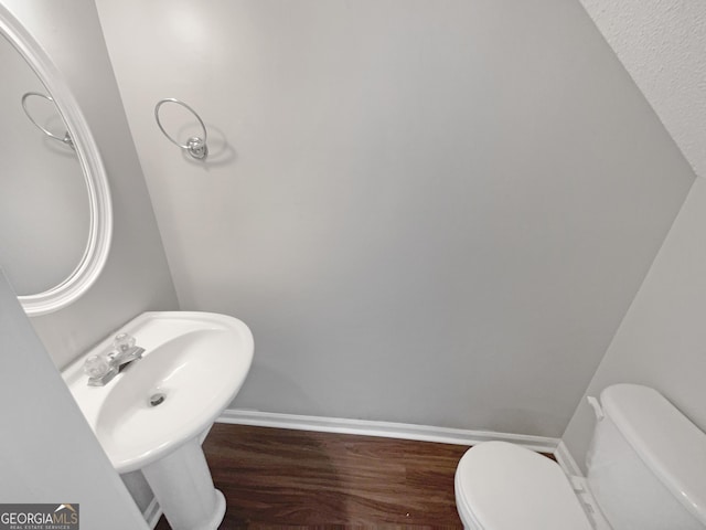 bathroom with a sink, toilet, baseboards, and wood finished floors