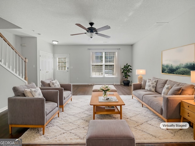 living area with a ceiling fan, a textured ceiling, wood finished floors, stairway, and baseboards