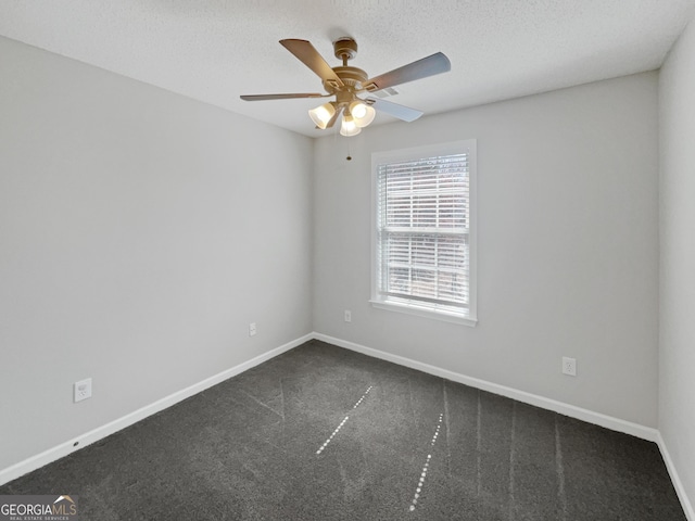 spare room with a textured ceiling, baseboards, a ceiling fan, and dark colored carpet