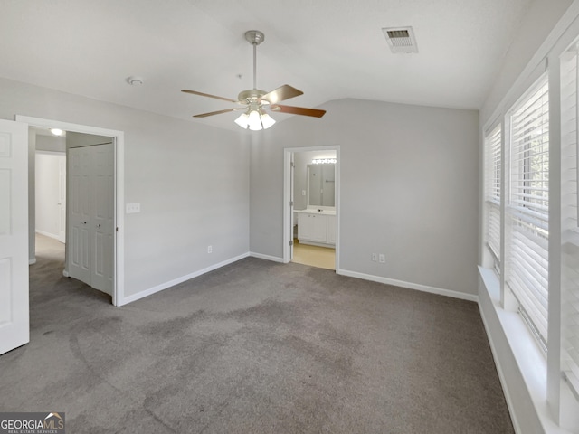 unfurnished bedroom with carpet, visible vents, baseboards, ensuite bath, and lofted ceiling