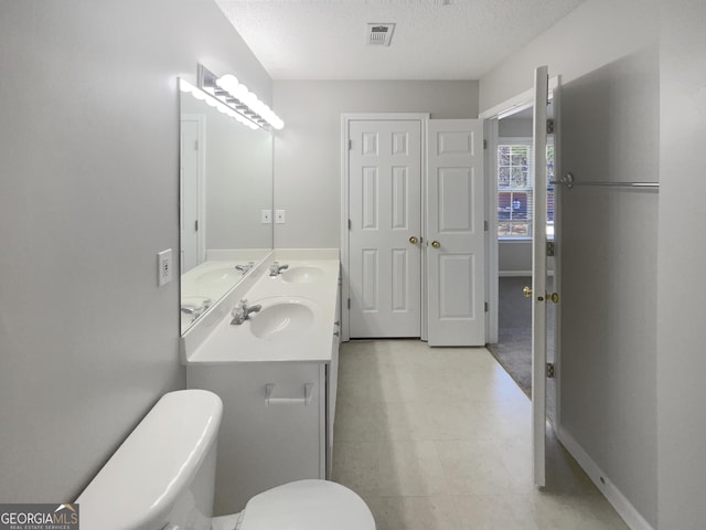 full bathroom featuring a sink, visible vents, toilet, and a textured ceiling