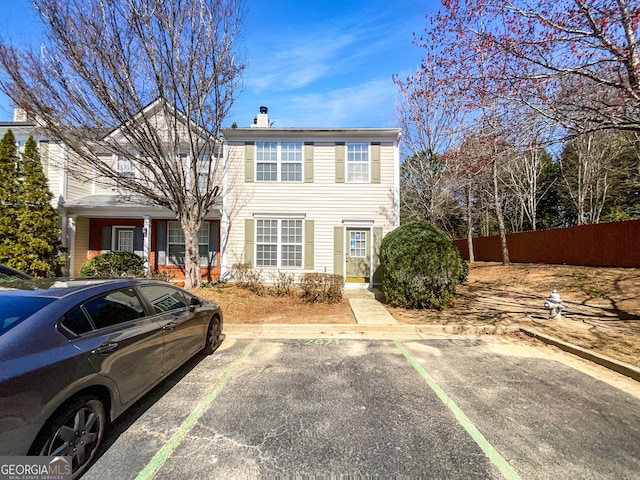 view of front of home featuring uncovered parking, fence, and a chimney