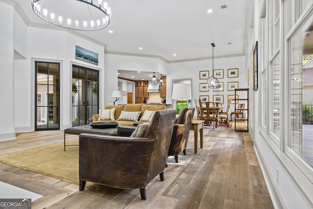 living room featuring a chandelier, french doors, ornamental molding, and wood-type flooring