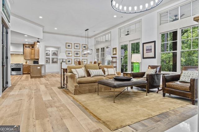 living room featuring a healthy amount of sunlight, light wood-type flooring, french doors, and a chandelier