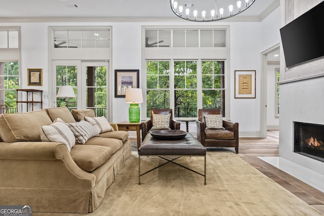 living room with hardwood / wood-style floors, a notable chandelier, a towering ceiling, and a fireplace