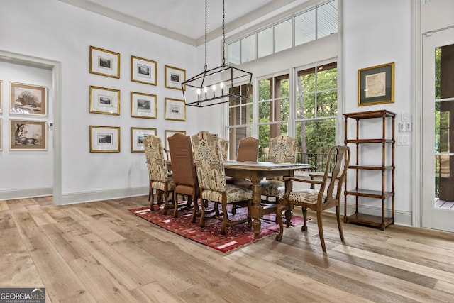 dining space with light hardwood / wood-style floors and an inviting chandelier