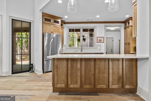 kitchen with pendant lighting, stainless steel refrigerator, a wealth of natural light, and sink