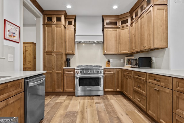 kitchen featuring premium range hood, light hardwood / wood-style flooring, and appliances with stainless steel finishes