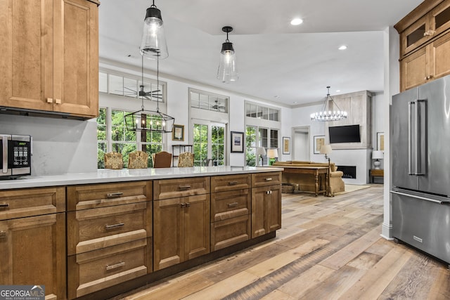 kitchen featuring hanging light fixtures, stainless steel appliances, an inviting chandelier, backsplash, and light hardwood / wood-style floors