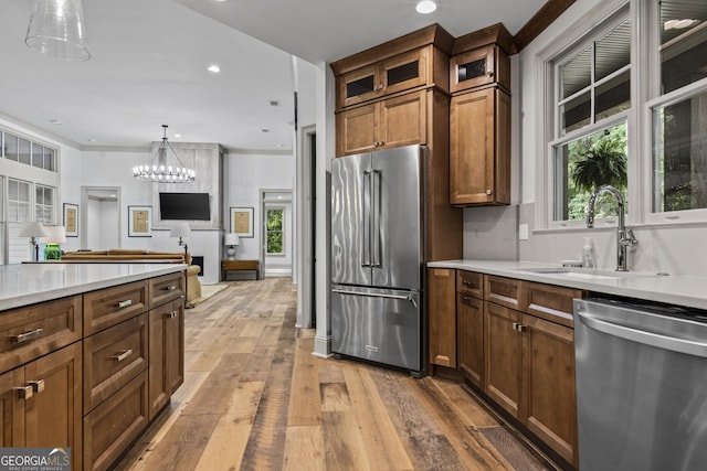 kitchen with sink, stainless steel appliances, an inviting chandelier, decorative light fixtures, and light wood-type flooring