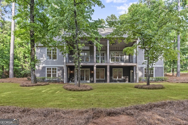 back of property featuring a yard, a balcony, and ceiling fan