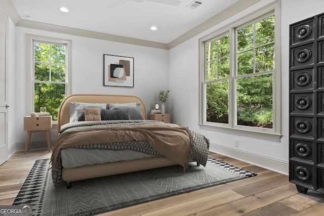 bedroom with multiple windows, light hardwood / wood-style flooring, and ceiling fan