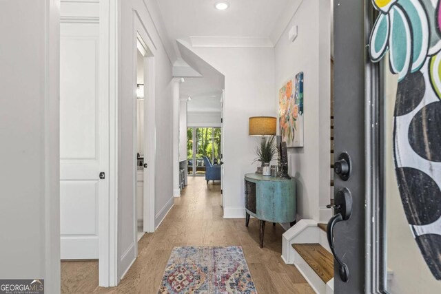 hallway with light hardwood / wood-style flooring and crown molding