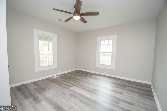 empty room with wood-type flooring, a wealth of natural light, and ceiling fan