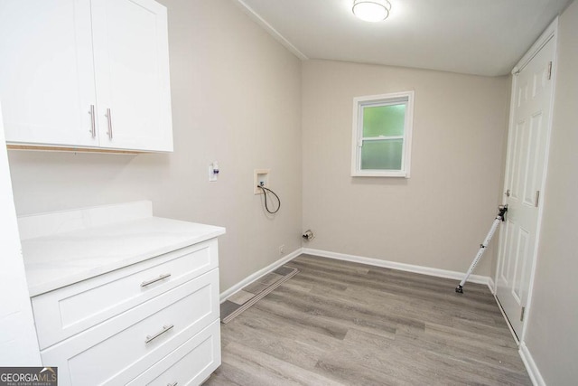 washroom with hookup for a washing machine, cabinets, and light hardwood / wood-style floors