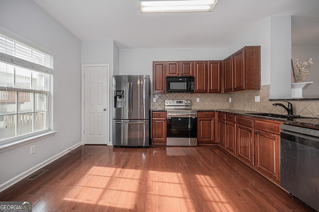 kitchen featuring appliances with stainless steel finishes, a healthy amount of sunlight, and dark hardwood / wood-style flooring