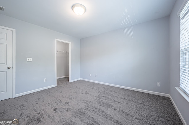 unfurnished bedroom featuring carpet floors, a closet, and a walk in closet