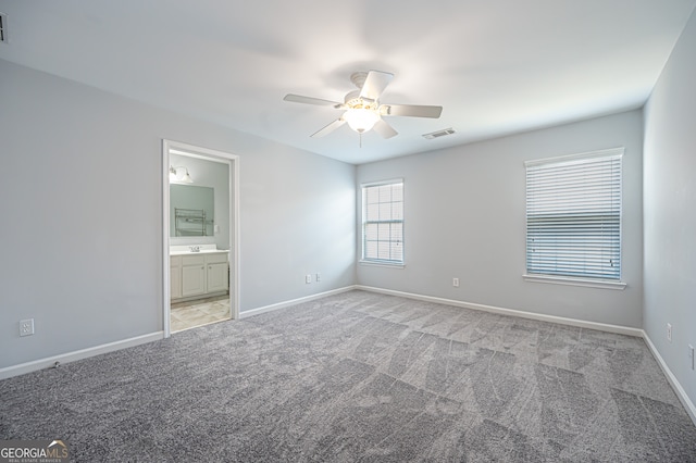 unfurnished bedroom featuring ceiling fan, light colored carpet, and ensuite bathroom