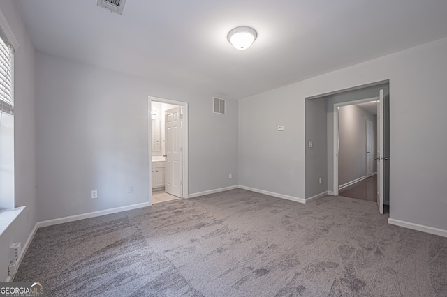 unfurnished bedroom featuring ensuite bath and light carpet