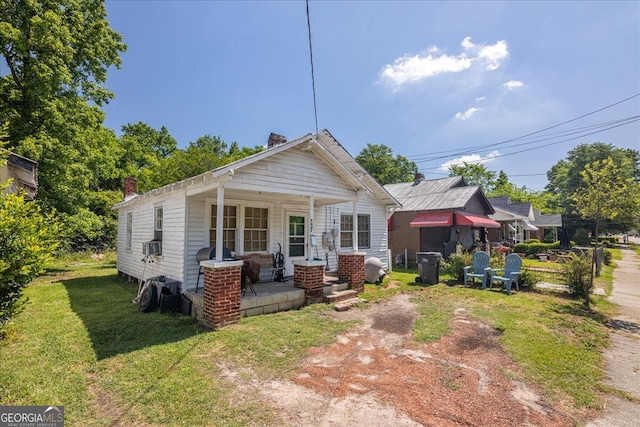 back of house with covered porch and a lawn