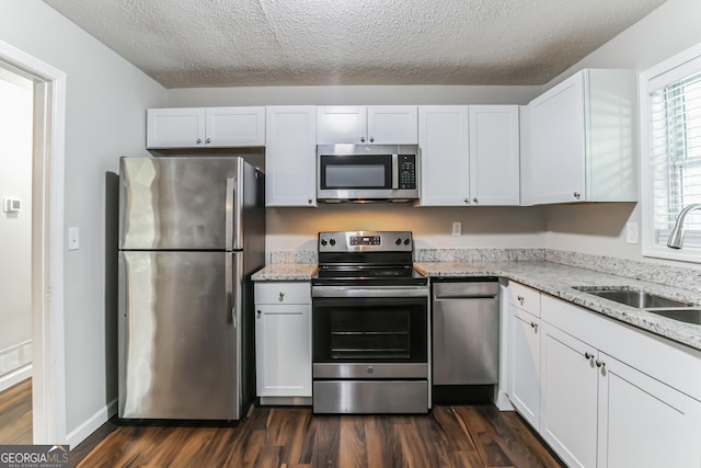 kitchen featuring light stone counters, stainless steel appliances, sink, and white cabinets