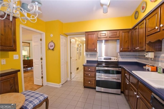 kitchen with tasteful backsplash, dishwashing machine, sink, light tile patterned floors, and stainless steel stove