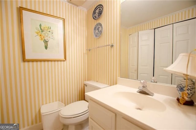 bathroom with toilet, vanity, and ornamental molding