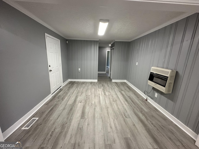 unfurnished living room with light wood-type flooring, ornamental molding, a textured ceiling, and heating unit