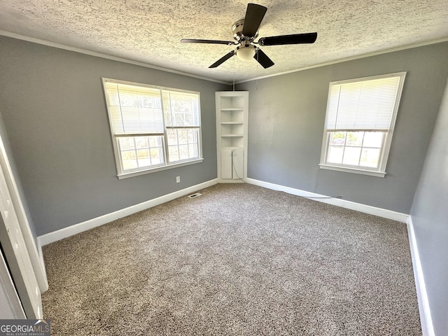 carpeted empty room with plenty of natural light, crown molding, and a textured ceiling