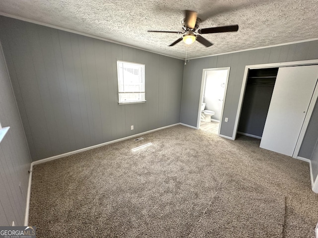 unfurnished bedroom featuring carpet, ceiling fan, a textured ceiling, connected bathroom, and a closet