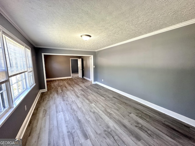 unfurnished room featuring a textured ceiling, hardwood / wood-style flooring, and ornamental molding