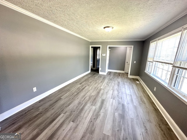 empty room featuring wood-type flooring, a textured ceiling, and ornamental molding